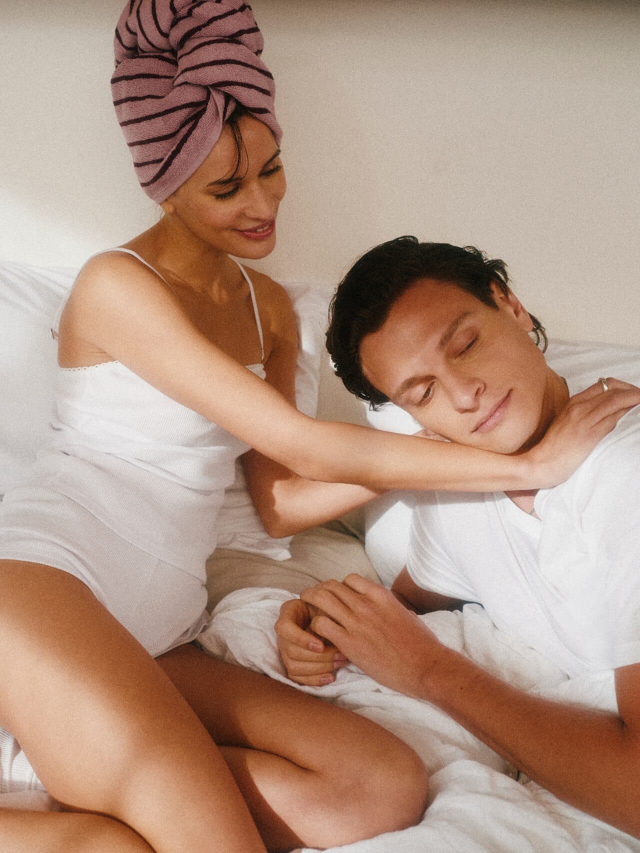 A woman rubbing her partner’s shoulders as they relax together in bed
