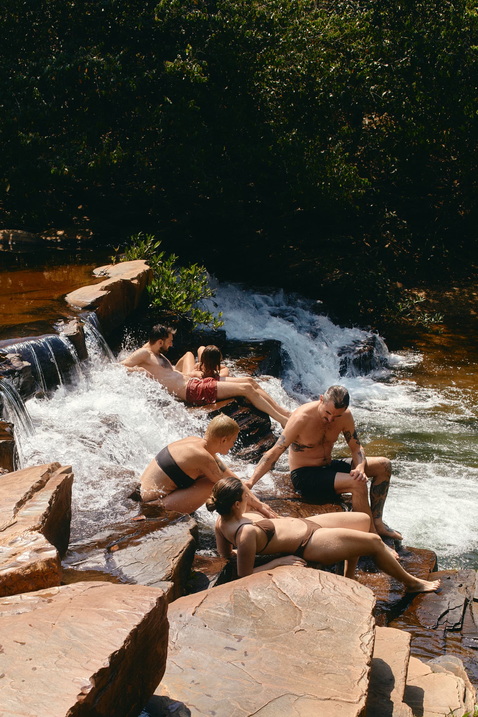 Friends relaxing together in a natural waterfall pool